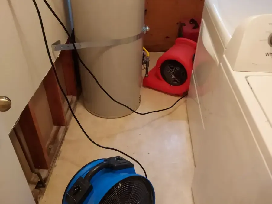 Air movers drying a laundry area after the wall behind the washer was opened