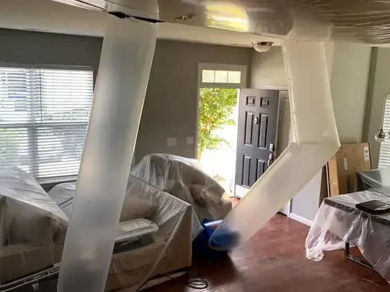 Drying ducts running past furniture wrapped in plastic sheeting