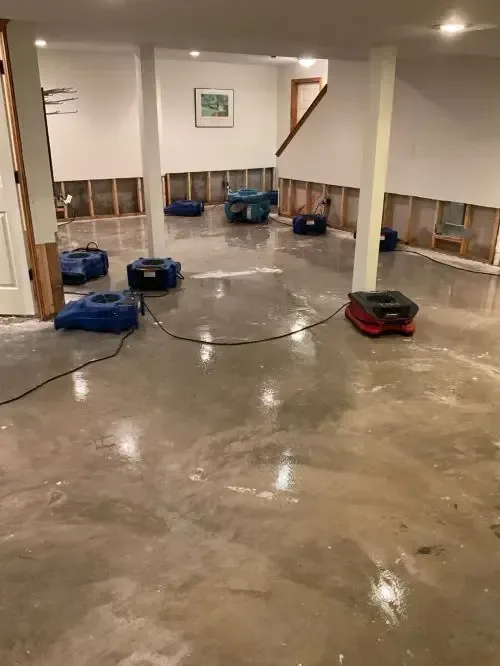 Air movers drying a flooded lower level with bottom drywall removed