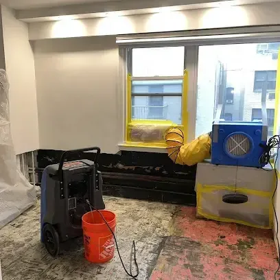 An air mover and a dehumidifier working in a room after the wet flooring was taken up