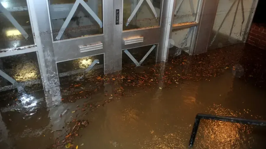 Storm water pushing into a storefront through its glass doors