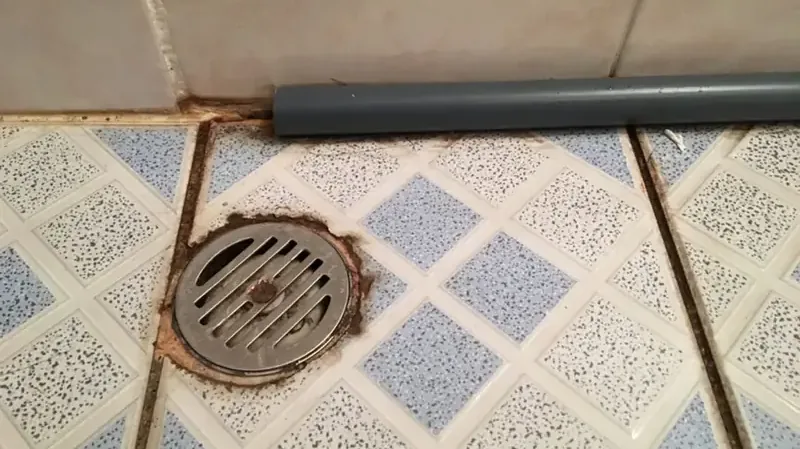 A floor drain set in a tiled basement floor, where a sewer backup comes up first